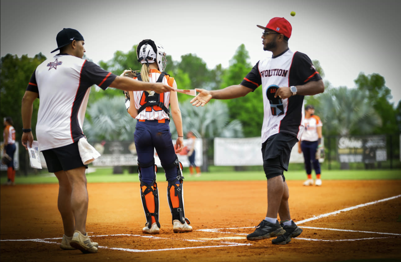 Revolution Black coaches meeting at home plate with a player during a 14U travel softball game
